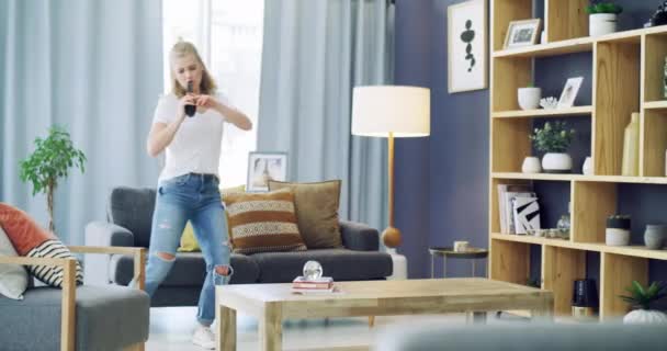 4k video footage of a happy young woman using headphones and singing with a brush at home. - Filmagem, Vídeo