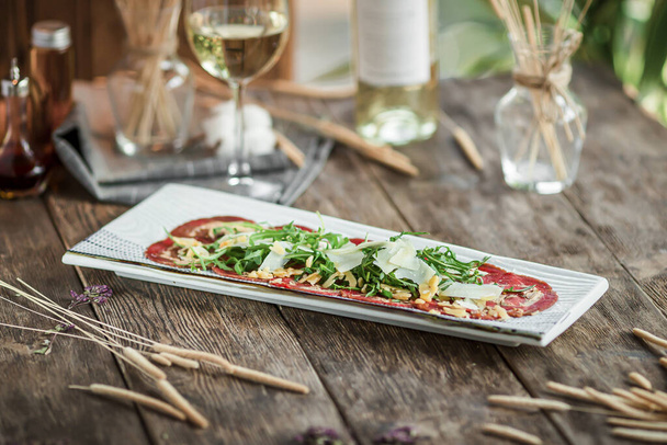 Portion of gourmet beef carpaccio appetizer with white wine - Photo, Image