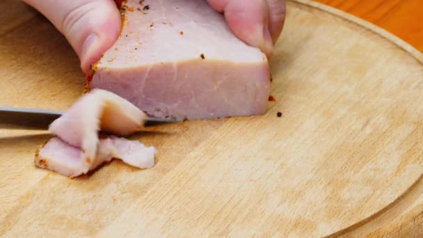 The chef cuts the ham. A man cuts fresh homemade smoked pork ham on a wooden table. Cooked piece of meat on a cutting board. Close-up. Concept of delicious food snacks and cooking. Copy space for text - Filmmaterial, Video
