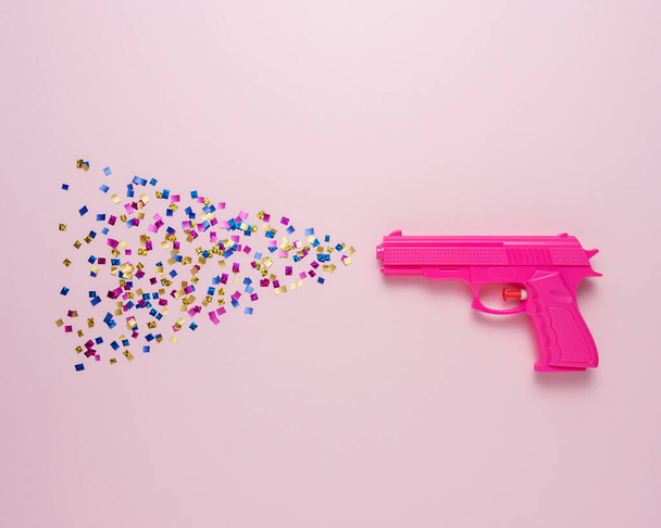 Creative background with pink gun and party confetti. Minimal holiday concept. - Fotoğraf, Görsel