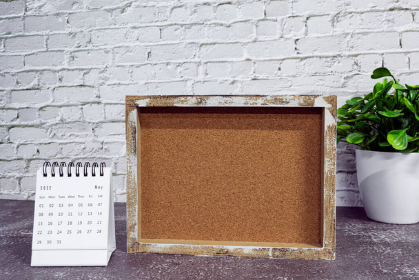 May 2022 white calendar with wooden frame and potted plant on wooden desk. Celebration and event concept. Copy space. - 写真・画像