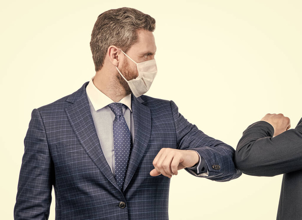 Businessman man in face mask use coronavirus alternative greeting touching elbows with colleague isolated on white, elbow bumping. - Valokuva, kuva