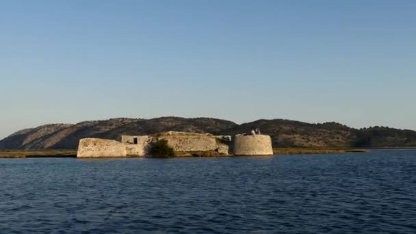 Ksamil, Albánie Malý motorový člun se blíží k hradu Ali Paša na pobřeží. - Záběry, video