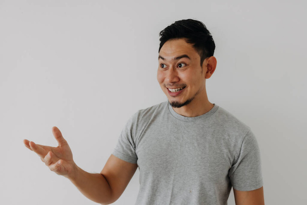 Happy asian man in grey t-shirt offer space of content for advertisement. - Photo, Image