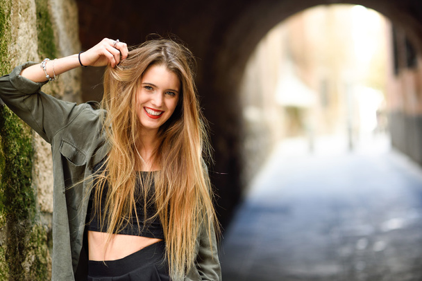 Chica rubia feliz sonriendo en el fondo urbano
 - Foto, Imagen