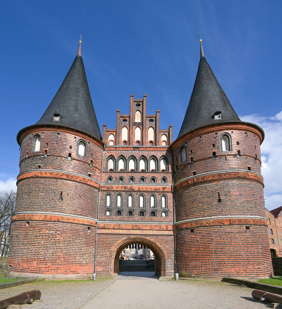 Historic Holstentor or Holsten gate of Lubeck in Germany, famous medieval landmark in red brick architecture, inscription Concordia domi foris pax (harmony inside, peace outside), blue sky - Foto, Imagem