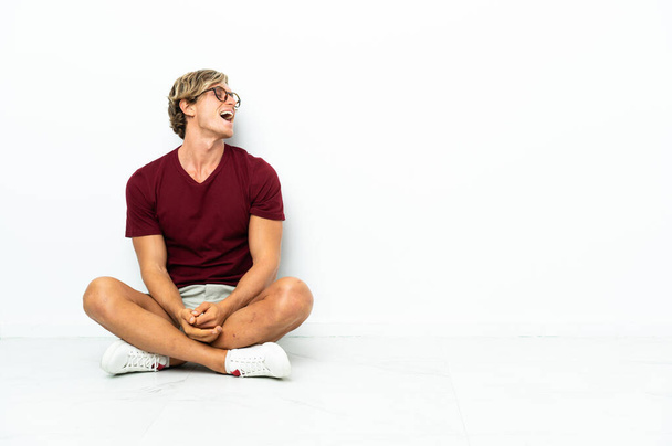 Young English man sitting on the floor laughing in lateral position - 写真・画像