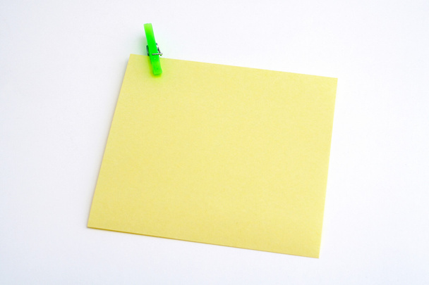 Isolated yellow paper with green clamp - Foto, Bild