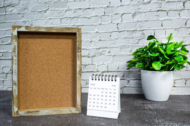 Juni 2022 witte kalender met houten frame en potplant op houten bureau. Feest en evenement concept. Kopieerruimte. - Foto, afbeelding