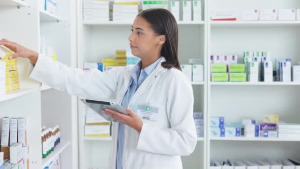 Egy fiatal női gyógyszerész leltározása egy gyógyszertárban egy tabletta használatával. Az orvos recepteket és gyógyszereket készít a klinikán vagy a gyógyszertárban. Egészségügyi szakember válogatás orvostudomány digitális eszközzel. - Felvétel, videó