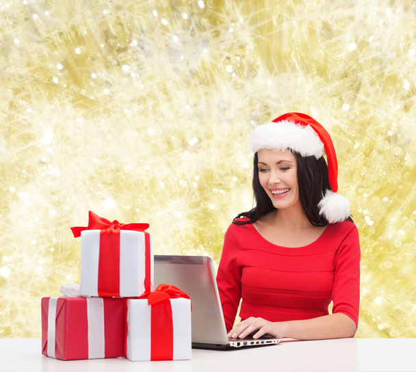 smiling woman in santa hat with gifts and laptop - Foto, Imagem