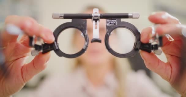 Optometrista probando ojos con una herramienta universal messbrille phoropter en la clínica de oftalmología. Primer plano profesional de la salud examinando, ajustando lentes de prescripción y corrigiendo la visión en una consulta. - Metraje, vídeo