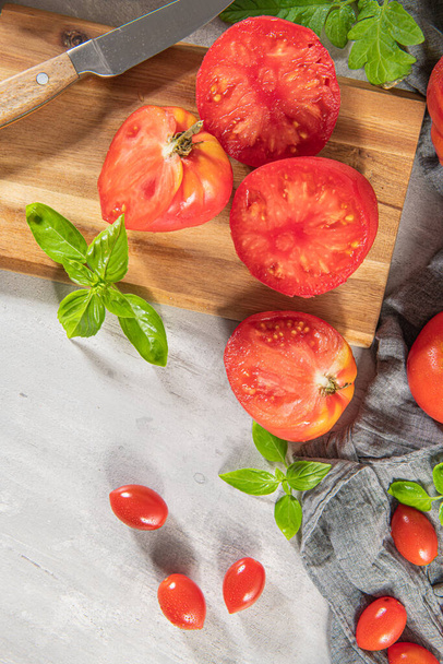 Duży wybór pomidorów na rustykalnym blacie kuchennym. Przygotowanie sosu pomidorowego z cebulą i bazylią - Zdjęcie, obraz