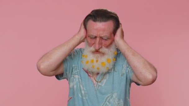Dont want to hear and listen. Frustrated annoyed irritated senior man covering ears and gesturing no, avoiding advice ignoring unpleasant noise loud voices. Grandfather on pink studio wall background - Záběry, video