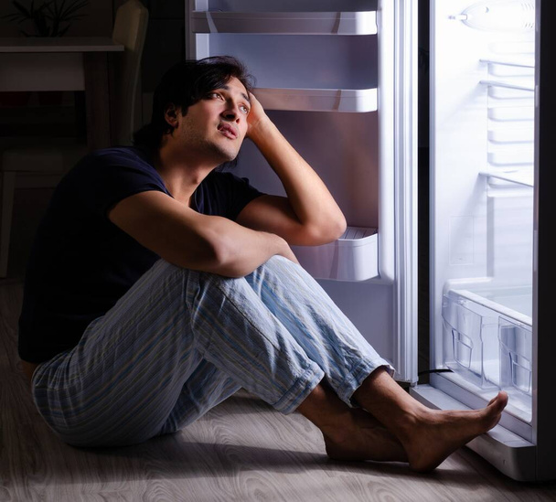 A férfi, aki megszegi a diétát éjszaka a hűtő közelében. - Fotó, kép