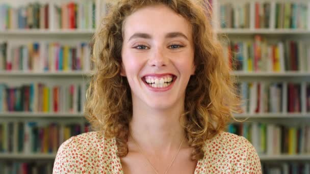 Face portrait of laughing, funky and cool student smiling in educational institute. Closeup headshot of young, trendy woman with happy facial expression standing in school library or community centre. - Filmati, video