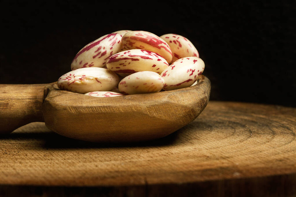 Pinto beans in a wooden spoon on black background  in a close up view - Φωτογραφία, εικόνα