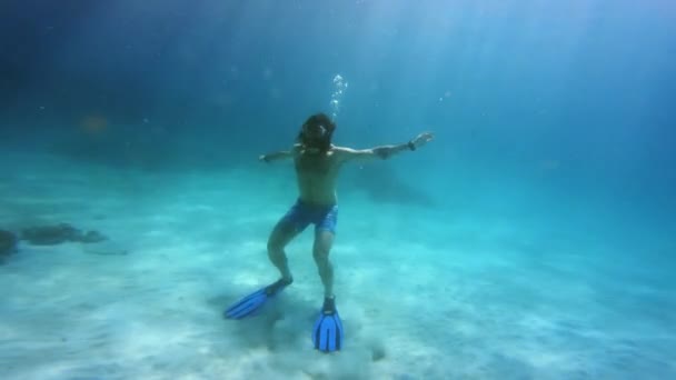 4k video footage of a confident young man wearing snorkeling gear while swimming back up the surface inside of the ocean. - Footage, Video
