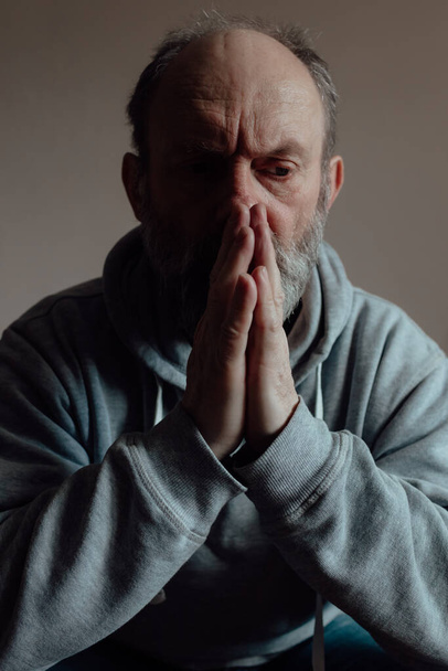 Ukrainian worried middle aged man folded his hands in prayer and thinks intently. Unhappy mature older grandfather at home. - Fotoğraf, Görsel