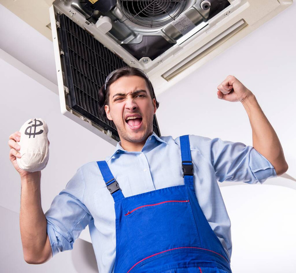 O jovem reparador reparando teto unidade de ar condicionado - Foto, Imagem