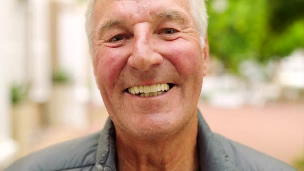 Laughing man showing white teeth or dentures after dental treatment in the city. Closeup headshot and face portrait of a happy, smiling mature man. Content, confident and proud during a day in town. - Imágenes, Vídeo