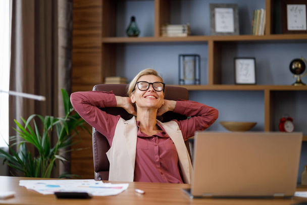 Happy businesswoman surprised by the good news while looking at laptop sitting at office.Manager enjoying success, celebrating victory,make good deal, get profit. The rise of cryptocurrencies concept. - Foto, imagen