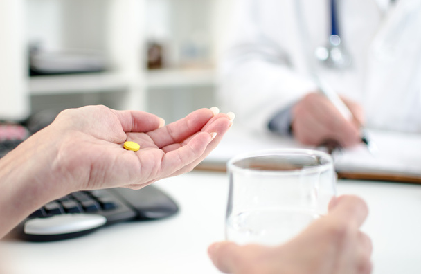 Patient holding pill and glass of water - Photo, Image
