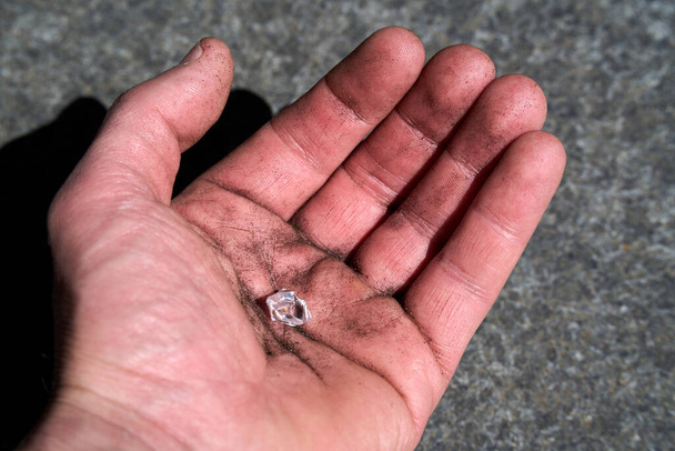 Χέρι με ένα ψεύτικο διαμάντι που προσποιείται ότι βρέθηκε στη γη. Υψηλής ποιότητας φωτογραφία - Φωτογραφία, εικόνα