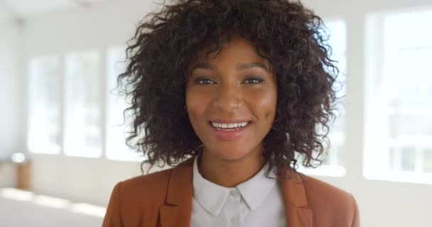 A cheerful businesswoman laughing inside an empty room. Beautiful young Afro American woman or corporate worker in a stylish business suit. A creative entrepreneur with happy expression on her face. - Filmmaterial, Video