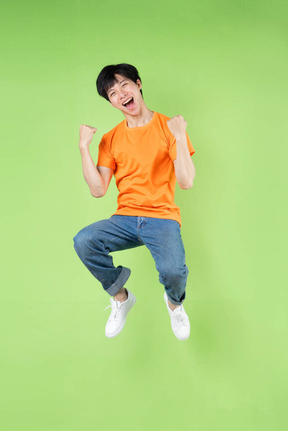 young asian man jumping , isolated on green background - Foto, imagen