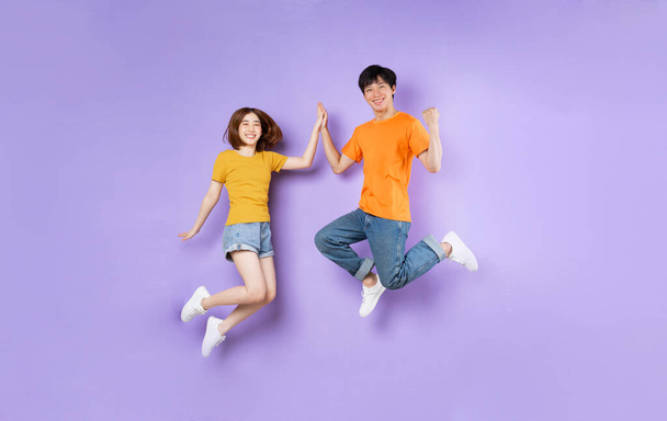 Portrait of a couple jumping up, isolated on purple background - Photo, Image