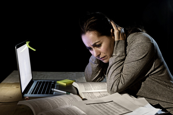 Απελπισμένοι εικοσιπεντάχρονο φοιτητή κορίτσι στο άγχος για τη μελέτη των εξετάσεων με βιβλία και υπολογιστή laptop αργά το βράδυ - Φωτογραφία, εικόνα