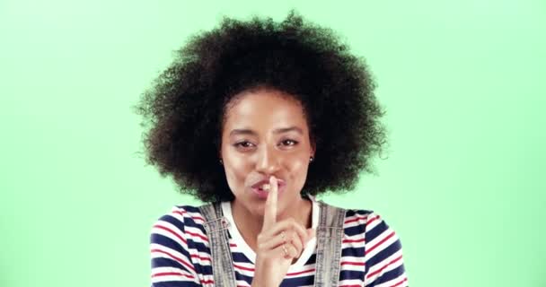 4k video filmación de una joven mujer poniendo su dedo en sus labios sobre un fondo verde estudio. - Imágenes, Vídeo