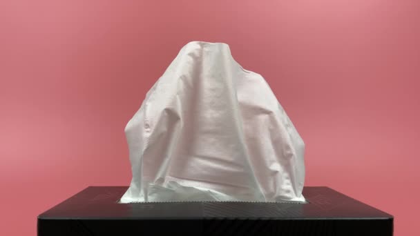 Movimento lento, a mão de uma pessoa retira um pedaço de tecido da caixa de papel tissue isolado em fundo rosa. - Filmagem, Vídeo