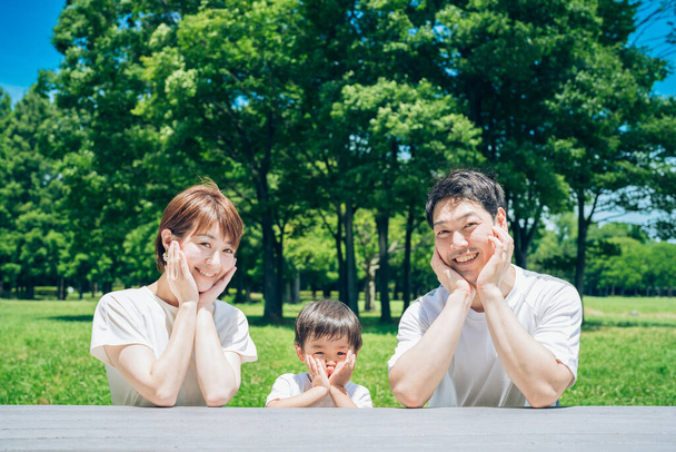 Family in the same pose in the park on fine day - 写真・画像