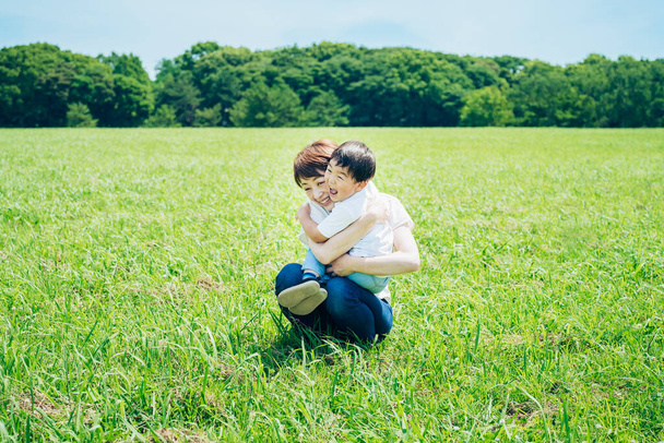 Mother hugging her boy in the green space on fine day - 写真・画像