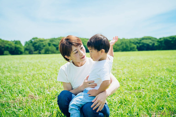 Mother hugging her boy in the green space on fine day - 写真・画像
