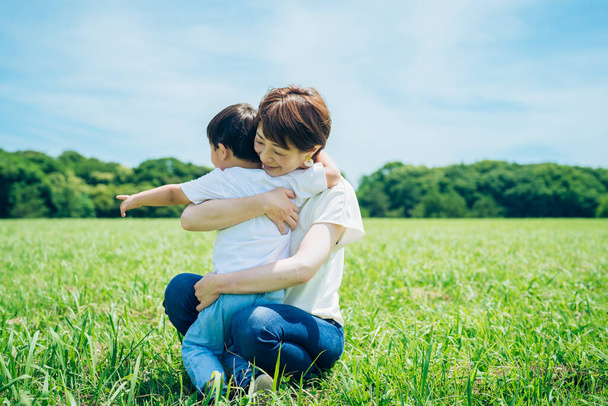 Η μητέρα αγκαλιάζει το αγόρι της στον πράσινο χώρο την ωραία μέρα - Φωτογραφία, εικόνα