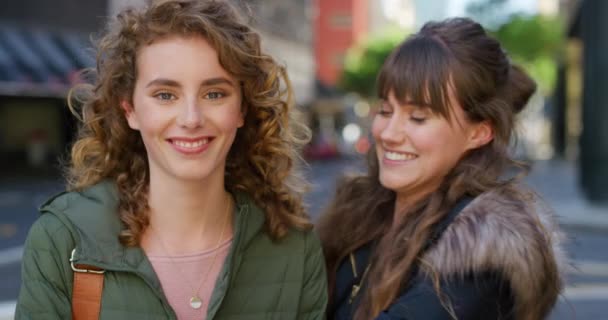Portrait of two smiling friends hugging and looking happy in the city. Faces of cheerful sisters bonding and having fun while traveling together. Excited females embracing in loving playful greeting. - Footage, Video