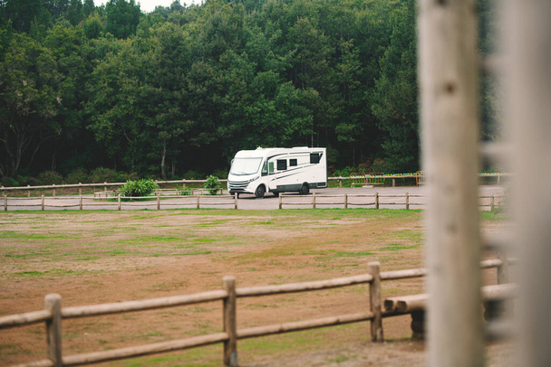 Modern camper motor home parked in the free nature alone. People enjoying travel and drive holiday vacation. Alternative off grid home and living lifestyle people. Van life and forest background - Foto, Imagem