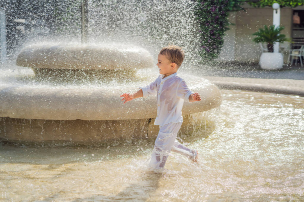 Happy boy plays in the street fountain. - 写真・画像