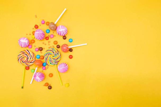 Colorful candies isolated on yellow backgroundg - Foto, afbeelding