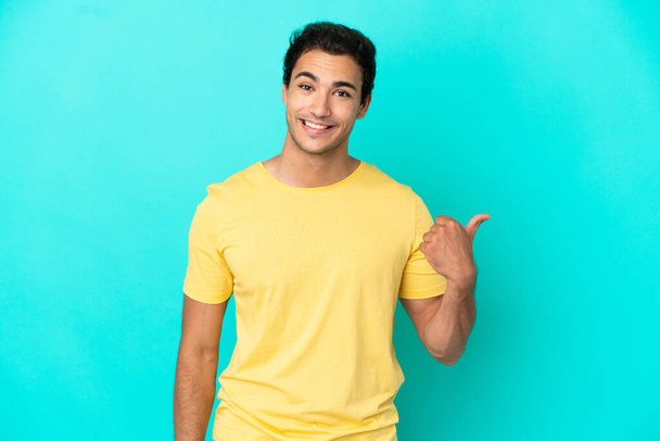 Caucasian handsome man over isolated blue background pointing to the side to present a product - Foto, afbeelding