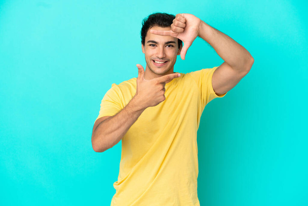 Caucasian handsome man over isolated blue background focusing face. Framing symbol - Photo, Image