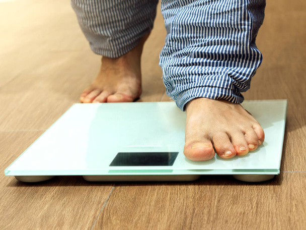 Male leg stepping on weigh scales. Healthy lifestyle, food and sport concept. Selective focus - Foto, Bild