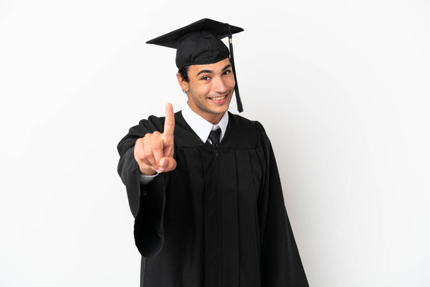 Graduado universitario joven sobre fondo blanco aislado mostrando y levantando un dedo - Foto, imagen