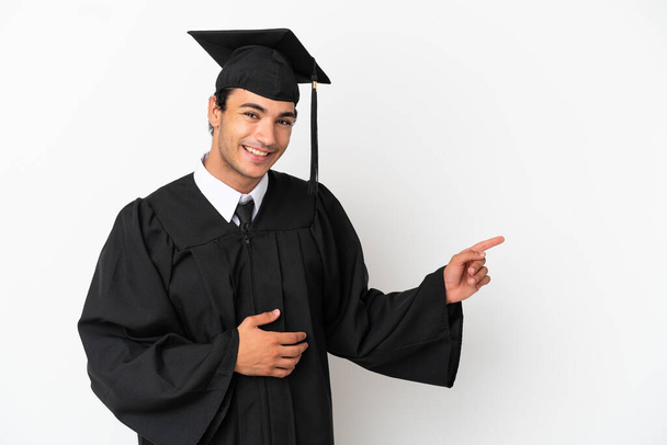 Молодий випускник університету над ізольованим білим тлом вказуючи пальцем на бік
 - Фото, зображення