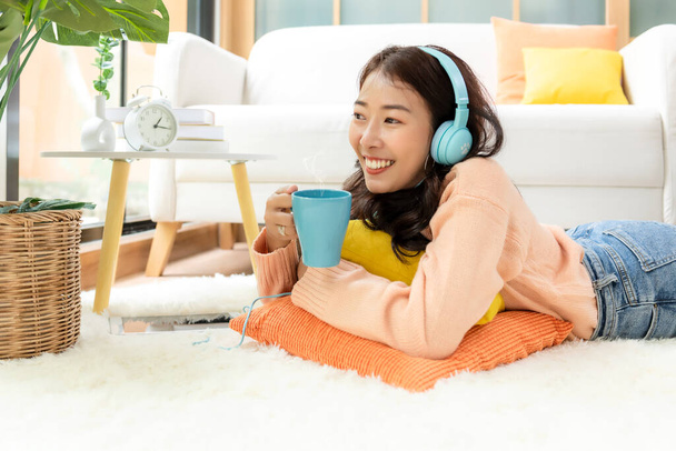Home lifestyle woman relaxing lying down in living room. Happy girl shopping and listen music on laptop for wellness and health in weekend holiday.  Lifestyle Concept - Фото, зображення