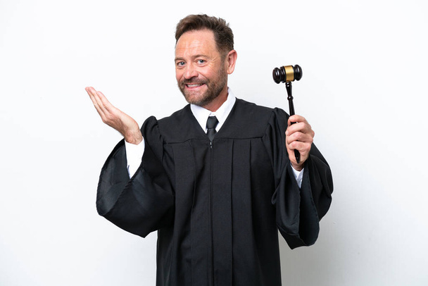 Μεσήλικας δικαστής άνθρωπος απομονωμένος σε λευκό φόντο απλώνει τα χέρια προς την πλευρά για την πρόσκληση να έρθει - Φωτογραφία, εικόνα