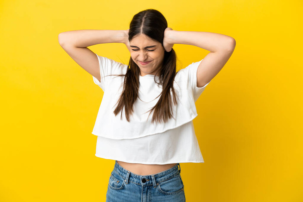 Young caucasian woman isolated on yellow background frustrated and covering ears - Photo, Image
